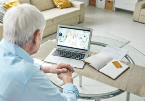 man sitting at a table looking at a laptop