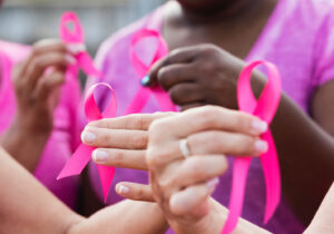 Hands holding pink ribbons
