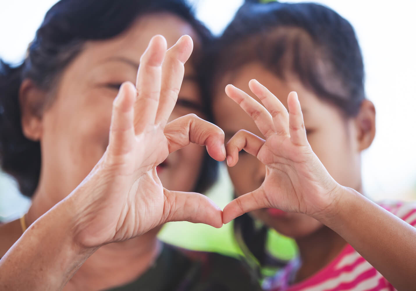 Woman and child making heart symbol