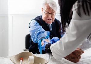 Nurse drawing blood from elderly man