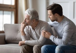 Adult son comforts senior father