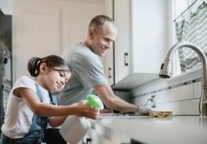 Father and daughter cleaning kitchen surfaces